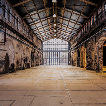 Eine riesige alte Fabrikhalle mit rechts und links Arkadengängen mit Rundbögen