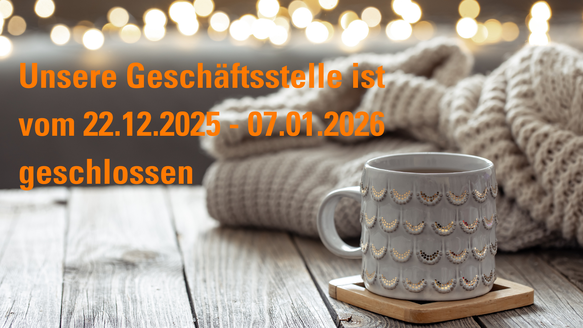 Eine kuschelige Wolldecke und eine Teetasse ist auf einem Holztisch- darüber steht Unsere Geschäftsstelle ist vom 22.12.25 - 07.01.2026 geschlossen