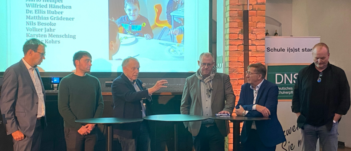 Mehrere Redner vor einem Bildschirm, der ein Kind zeigt beim Kongress für Schulverpflegung