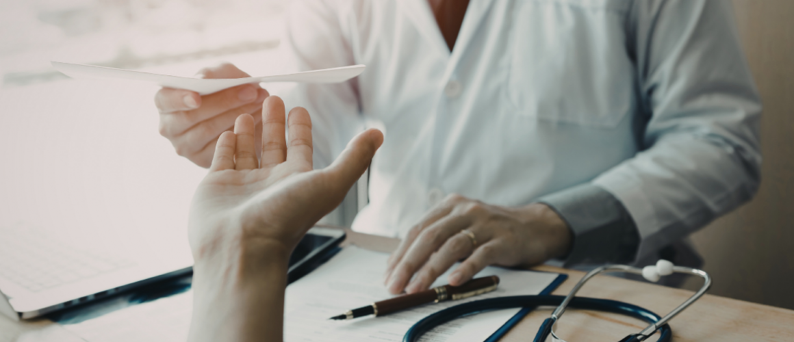 Arzt reicht dere Hand einer Patientin eine Überweisung