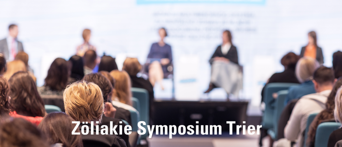 Podium mit Rednern und davor viele Zuhörer - darunter steht Zöliakie Symposium Trier
