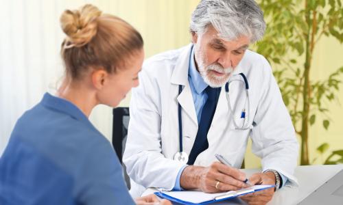 Älterer Arzt bespricht Unterlagen mit Patientin