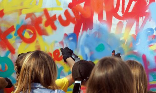 Gruppe Jugendlicher sprüht Graffiti an eine Wand