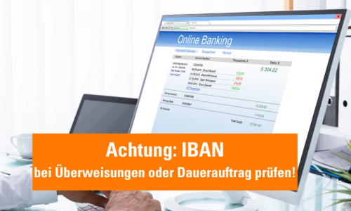 Computer mit Display für Online Banking und orangener Hinweis: Neue IBAN- bei Überweisungen und Dauerauftrag prüfen!